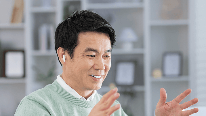 ワイヤレスイヤホンをつけ、にこやかに話している日本人男性講師の写真