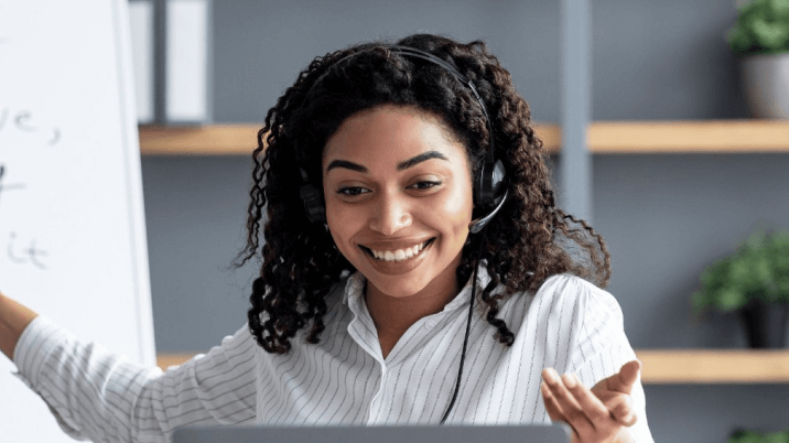 ヘッドセットをつけ、笑顔でパソコンを見ながら話しているネイティブ女性講師の写真