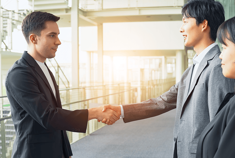 オフィスで同僚と相談しながら業務を進めるビジネスパーソン